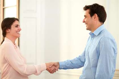 Portrait of professional man and woman giving hands greeting each other while smiling and standing on office background